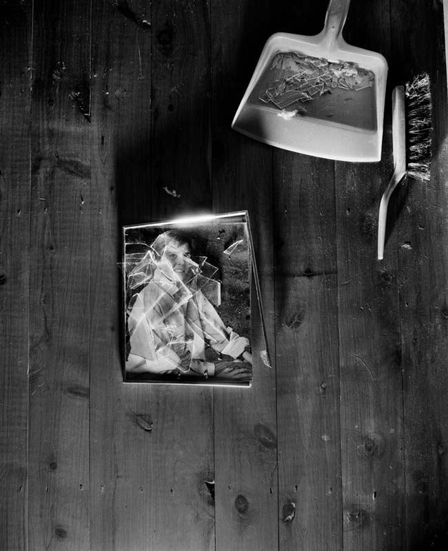 Framed photograph broken and smashed on the floor next to a dustpan and brush